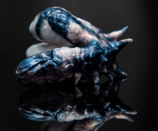 A blue and white sculpture of Dracul the Trans Male Packer, a Fantasticocks product, with a reflection on a black surface, emphasizing authentic selves.